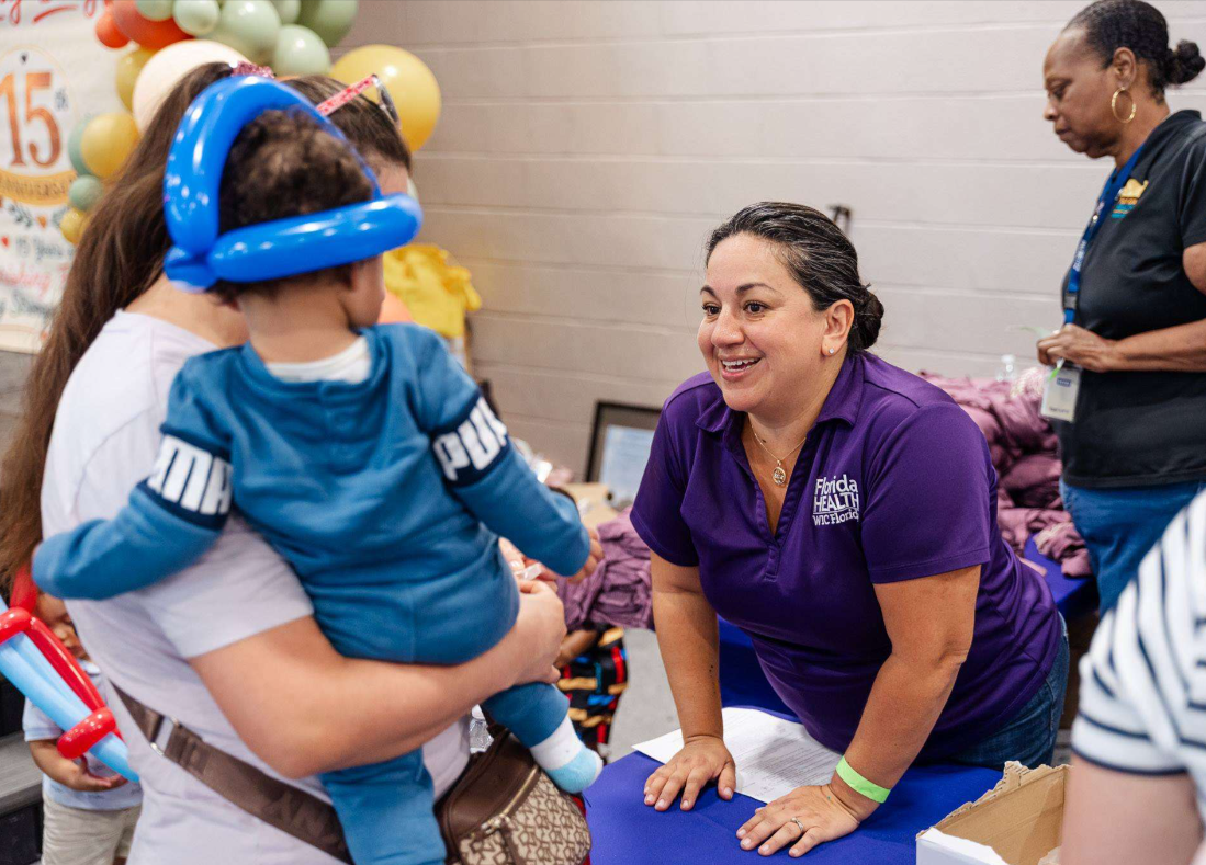 DOH-Miami-Dade staff member speaking with young child at event